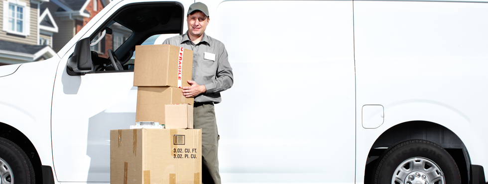 Delivery man standing beside van with boxes
